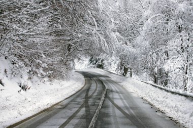 Kenarlarında kar yığınları olan boş yol.