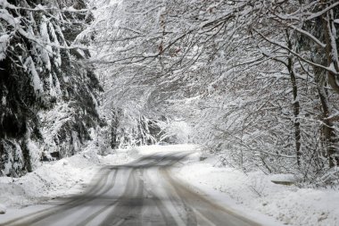 Kenarlarında kar yığınları olan boş yol.