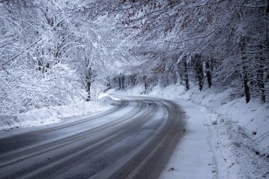 Kenarlarında kar yığınları olan boş yol.