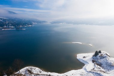 Romanya 'nın Colibita Gölü üzerinde kışın sihirli sisli gün doğumu.