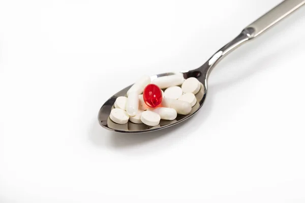 Pastillas blancas y rojas en una cuchara . — Foto de Stock