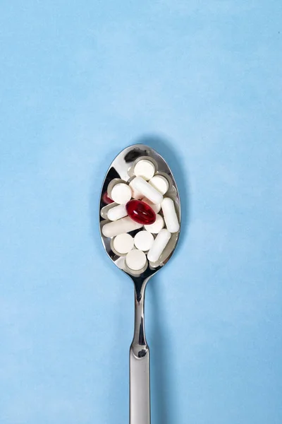 Pastillas blancas y rojas en una cuchara . — Foto de Stock