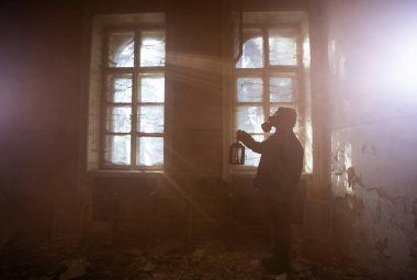 Yıkılmış bir binada gaz maskeli kıyamet sonrası hayatta kalanlar. Çevre felaketi, mahşer kavramı.