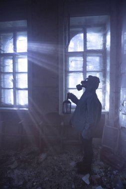 Yıkılmış bir binada gaz maskeli kıyamet sonrası hayatta kalanlar. Çevresel afet kavramından sonraki umut.