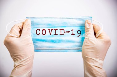 COVID-19 - Coronavirus hastalığı - 2019-nCoV. Üzerinde covid-19 yazılı tıbbi tek kullanımlık yüz maskesi.. 