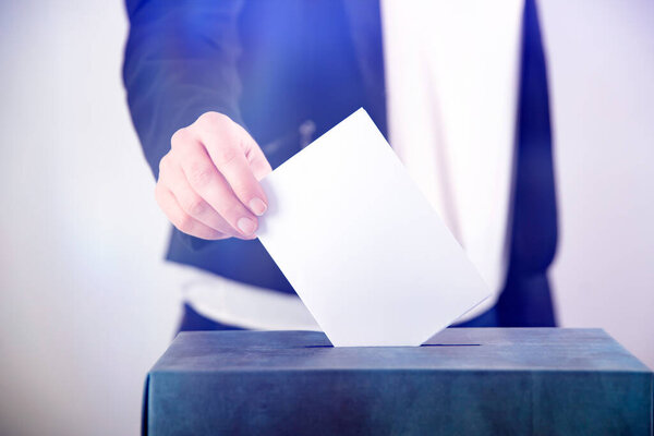 Рука избирателя, голосующего в урне для голосования. Концепция выборов.