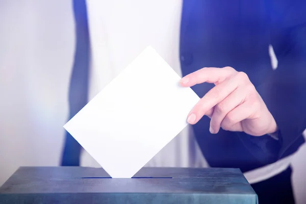 Hand of a voter putting vote in the ballot box. Election concept.