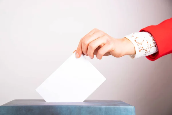 Hand of a voter putting vote in the ballot box. Election concept.