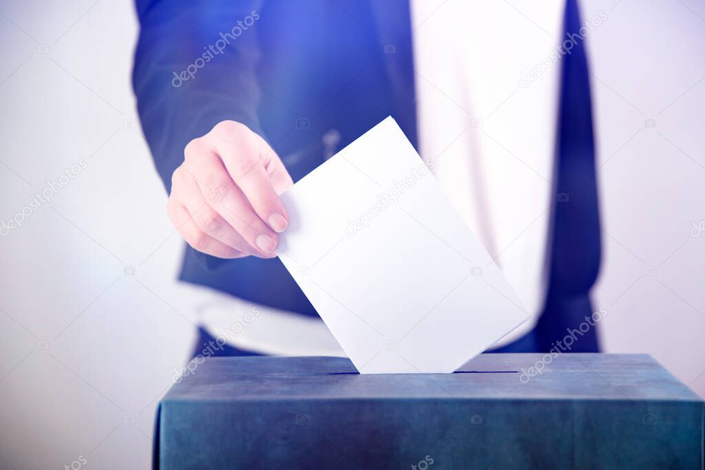 Hand of a voter putting vote in the ballot box. Election concept.