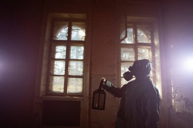 Yıkılmış bir binada gaz maskeli kıyamet sonrası hayatta kalanlar. Çevre felaketi, mahşer kavramı.