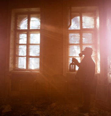 Yıkılmış bir binada gaz maskeli kıyamet sonrası hayatta kalanlar. Çevre felaketi, mahşer kavramı.