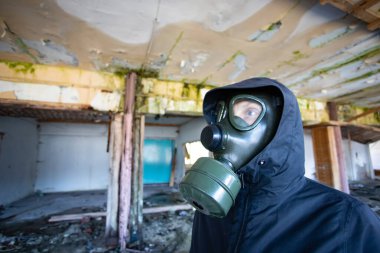 Yıkılmış bir binada gaz maskeli kıyamet sonrası hayatta kalanlar. Çevre felaketi, mahşer kavramı.