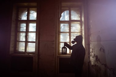 Yıkılmış bir binada gaz maskeli kıyamet sonrası hayatta kalanlar. Çevre felaketi, mahşer kavramı.