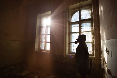 Yıkılmış bir binada gaz maskeli kıyamet sonrası hayatta kalanlar. Çevresel afet kavramından sonraki umut.