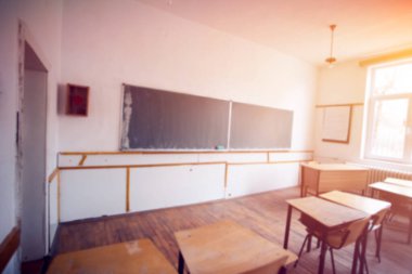 Okul konseptine geri dönelim. Sandalyeleri, masaları ve tahtası olan güneşli sınıfın bulanık görüntüsü.