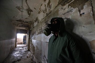  Yıkılmış bir binada gaz maskeli kıyamet sonrası hayatta kalanlar. Çevre felaketi, mahşer kavramı.