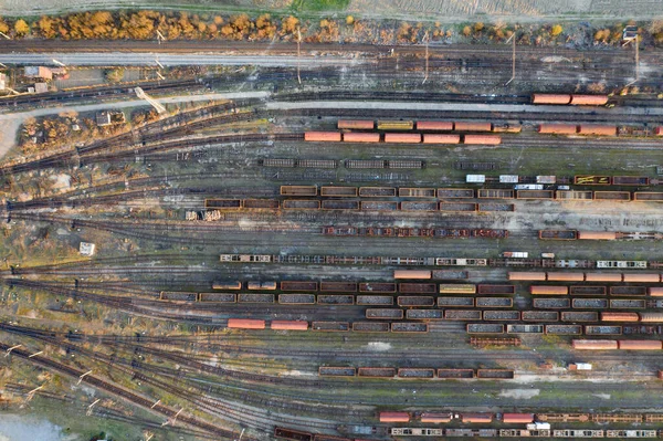 Aerial view of various railway carriage trains with goods on the railway station, top view.