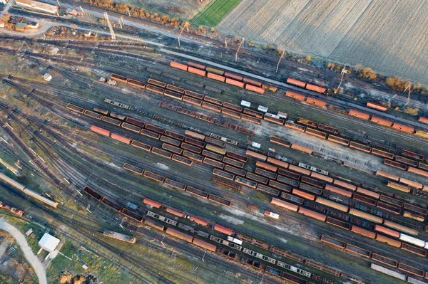 Aerial view of various railway carriage trains with goods on the railway station, top view.