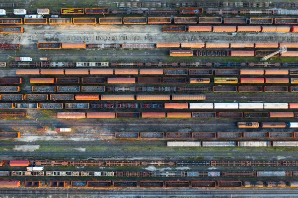 Aerial view of various railway carriage trains with goods on the railway station, top view.