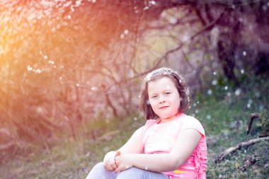 Çiçek açan ağaçların altında, bahçedeki sevimli küçük kız. Bahar taçyaprağı yağmuru.