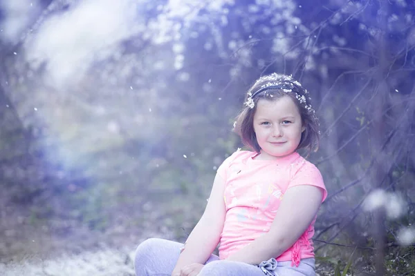 可爱的小女孩在花园里 在开花的树下 春花瓣的雨 — 图库照片