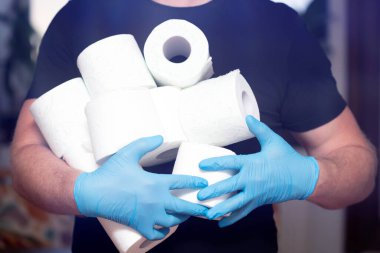İnsanlar koronavirüs salgınından dolayı evdeki karantina için tuvalet kağıdı stokluyorlar. Adamın elinde bir sürü tuvalet kağıdı var..