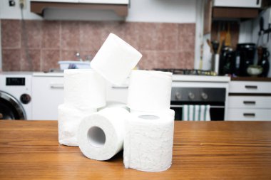 İnsanlar koronavirüs salgınından dolayı evdeki karantina için tuvalet kağıdı stokluyorlar. Mutfak masasında bir sürü tuvalet kağıdı var.