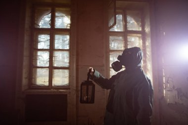 Yıkılmış bir binada gaz maskeli kıyamet sonrası hayatta kalanlar. Çevre felaketi, mahşer kavramı.