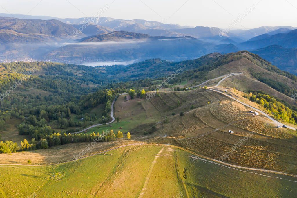 Aerial view of endless lush pastures of Transylvania. Beautiful romanian countryside with emerald green fields and meadows. Rural landscape on sunrise.