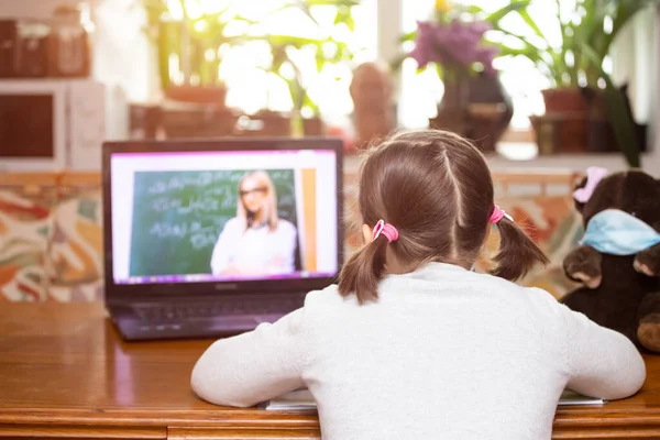 Distance learning-online education. School girl watching online education classes and doing school homework. COVID-19 pandemic forces children online learning.