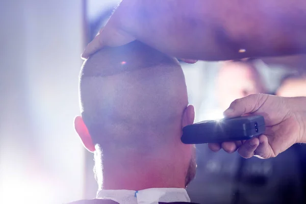 Man being trimmed with professional electric clipper machine in barbershop.Male beauty treatment concept.