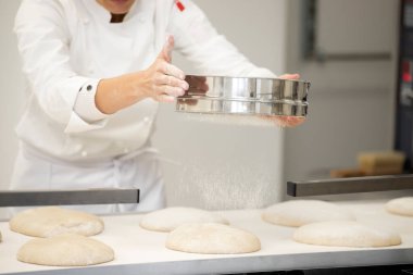 Fırında çalışan fırıncı geleneksel Fransız ekmeği ve pastası yapıyor..