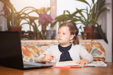 Uzaktan öğrenme çevrimiçi eğitim. Liseli kız çevrimiçi eğitim dersleri izliyor ve okul ödevi yapıyor. COVID-19 salgını çocukları çevrimiçi öğrenmeye zorluyor.