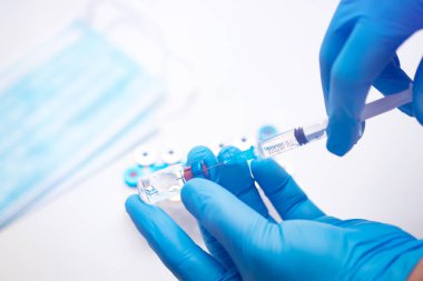 Bilim adamları ellerinde koronavirüs, covid-19 aşısı hastalığı olan mavi eldivenlerle klinik aşı aşısı için hazırlanıyorlar. İlaç ve uyuşturucu kavramı