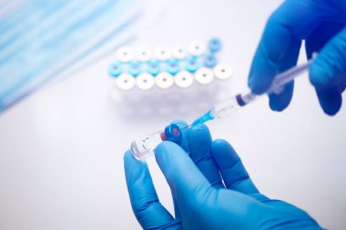 Bilim adamları ellerinde koronavirüs, covid-19 aşısı hastalığı olan mavi eldivenlerle klinik aşı aşısı için hazırlanıyorlar. İlaç ve uyuşturucu kavramı
