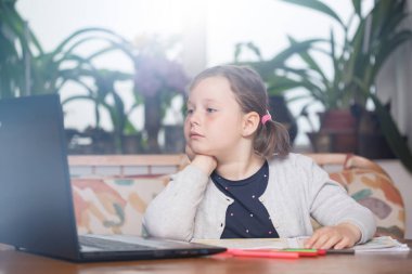 Uzaktan öğrenme çevrimiçi eğitim. Liseli kız çevrimiçi eğitim dersleri izliyor ve okul ödevi yapıyor. COVID-19 salgını çocukları çevrimiçi öğrenmeye zorluyor.