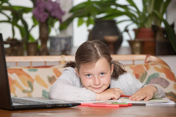 Distance learning-online education. School girl watching online education classes and doing school homework. COVID-19 pandemic forces children online learning.