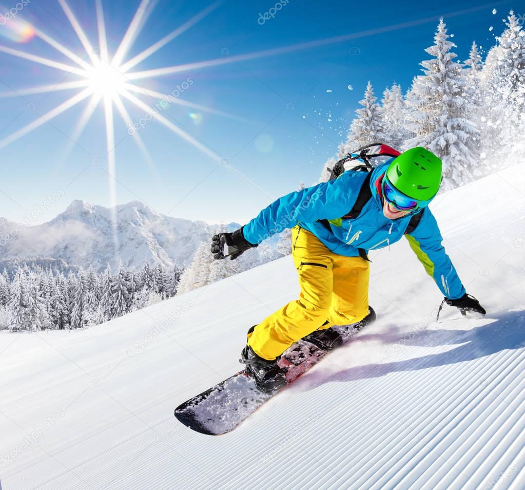 Snowboarder going downhill in high mountains