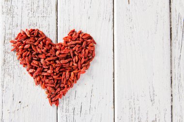 Goji meyveleri eski Beyaz ahşap masa üzerinde bir kalp olarak.