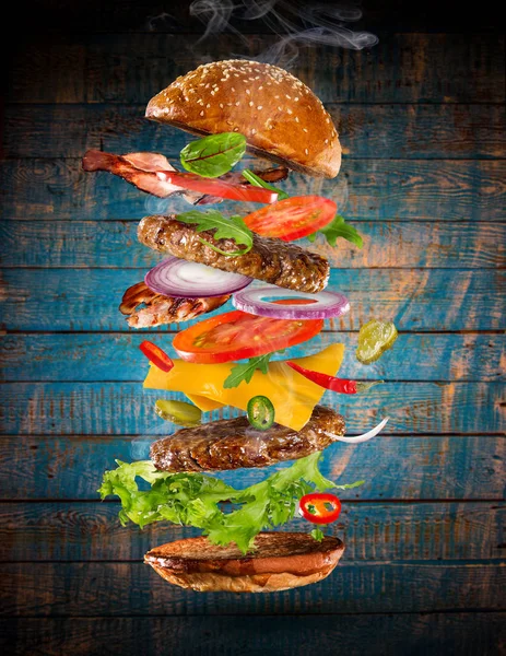 Grote smakelijke hamburger met vliegende ingrediënten. — Stockfoto