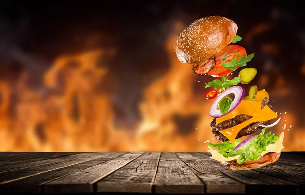 Gran hamburguesa sabrosa con ingredientes voladores . — Foto de Stock