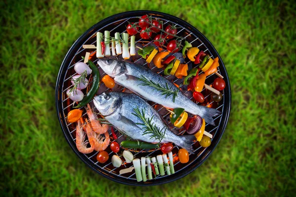 Pescados de mar a la parrilla con verduras, pinchos y langostinos en una parrilla de barbacoa . — Foto de Stock