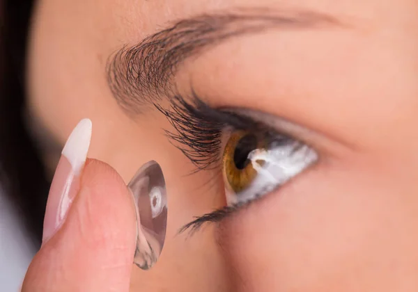 Молода жінка кладе контактну лінзу в очі . — стокове фото