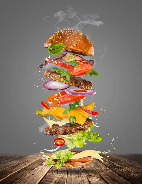 Big gustoso hamburger con ingredienti volanti . — Foto Stock