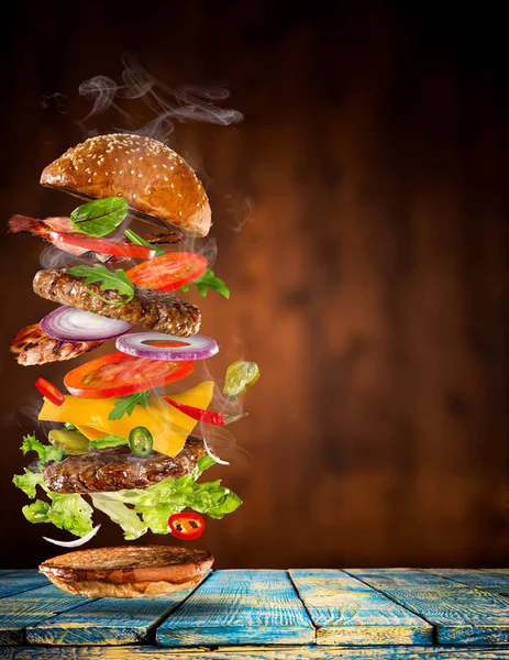 Stor velsmagende burger med flyvende ingredienser . - Stock-foto