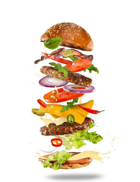 Grote smakelijke hamburger met vliegende ingrediënten. — Stockfoto
