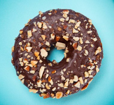 Pastel mavi arka plan üzerinde renkli sprinkles ile sırlı çörek.