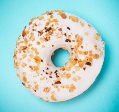 Pastel mavi arka plan üzerinde renkli sprinkles ile sırlı çörek.