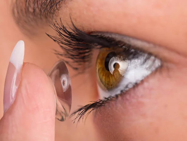 Jovem mulher colocando lente de contato em seu olho. — Fotografia de Stock