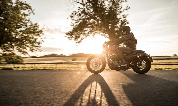 Hombre montando motocicleta deportiva durante la puesta del sol . — Foto de Stock